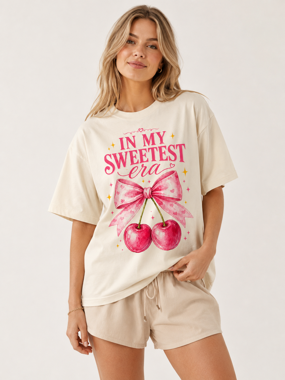 Woman wearing a cream T-shirt with pink cherry graphic and 'In My Sweetest Era' text